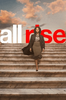 a woman is walking up a set of stairs with the word all rise in the background