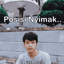 a man sitting in front of a brick wall with the words posisi nyimak