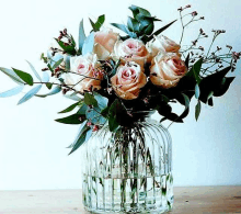 a vase filled with water and flowers on a wooden table .