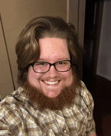 a man with a beard and glasses is smiling