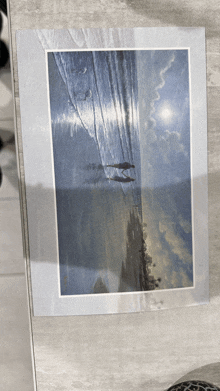 a picture of a beach with a boat in the water is on a table