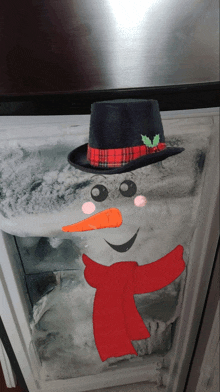 a snowman wearing a top hat and scarf is sticking out of a fridge