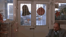 a man sits at a table in front of a door that has a sign on it that says ' happy new year '