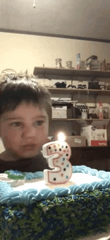 a young boy is blowing out a number three candle on a birthday cake