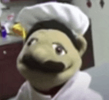 a stuffed animal with a chef 's hat and mustache is standing in a kitchen .