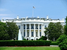 the white house with a fountain in front of it and a flag on top of it .