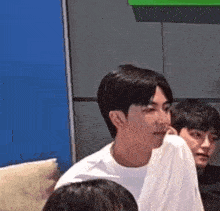 a man in a white shirt is sitting in front of a group of people in a room .