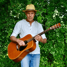 a man wearing a straw hat is holding a guitar