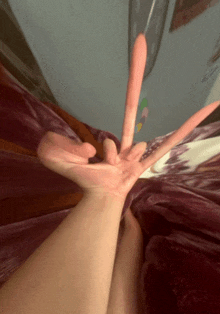 a person laying on a bed making a hand gesture with their fingers