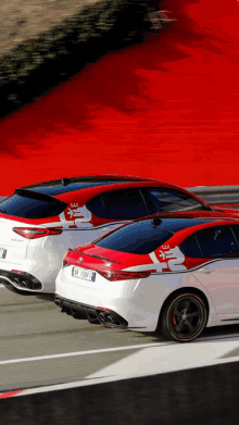 two alfa romeo cars are driving down a road with a red background