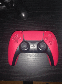 a red and black playstation controller sitting on a table