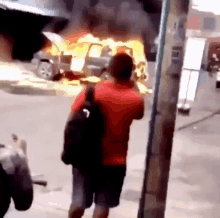 a man standing in front of a burning car