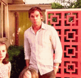 a man in a white shirt is standing in front of a pink fence