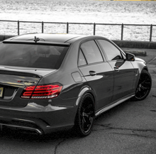 a gray amg car is parked in front of the water