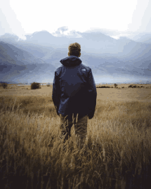 a person in a north face jacket stands in a field