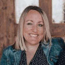 a woman is wearing a denim jacket and polka dot shirt and smiling .