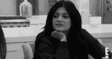 a black and white photo of a woman sitting at a table .