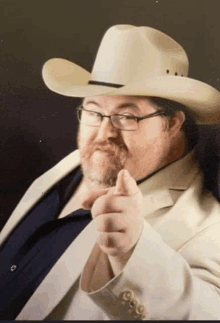 a man wearing a cowboy hat and glasses points his finger at the camera