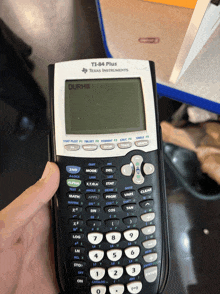 a texas instruments ti-84 plus calculator is being held by a person