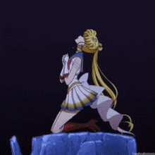 a girl in a sailor moon outfit is kneeling down on a rock