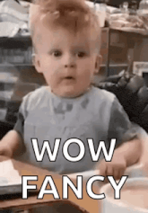 a baby is sitting at a table and making a funny face while saying wow fancy .