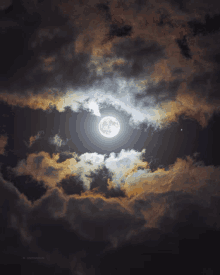 a full moon is surrounded by clouds in a dark night