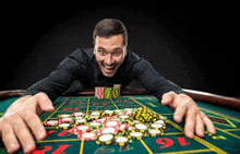 a man is playing roulette at a casino table with a pile of chips .