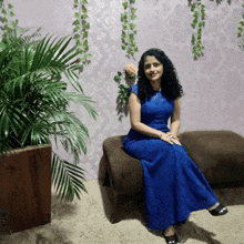 a woman in a blue dress is sitting on a couch