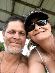 a man and a woman posing for a picture with the woman wearing sunglasses