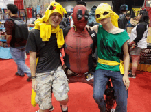 a man in a deadpool costume poses for a picture with two other people