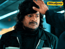a man with long hair and a mustache is being touched by another man with a yellow sign that says twickreddy on it