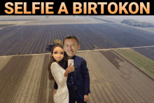 a man and woman taking a selfie in front of a field with the words selfie a birtokon