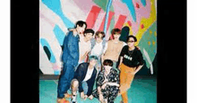 a group of young men are posing for a picture in front of a colorful wall .