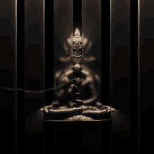 a statue of a man sitting in a lotus position is behind bars