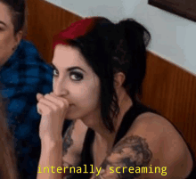 a woman with red and black hair is covering her mouth with her hand and the words internally screaming are below her