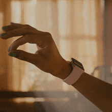 a woman 's hand with green nail polish and a watch on her wrist