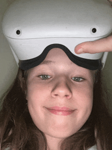 a young girl wearing a virtual reality headset looks at the camera