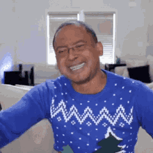 a man wearing a blue sweater with a christmas tree on it