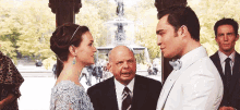 a man and a woman are standing next to each other and looking at each other in front of a fountain .