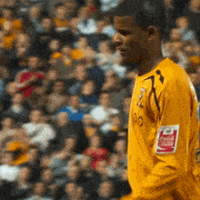 a soccer player wearing a yellow jersey with a coca cola logo on his arm