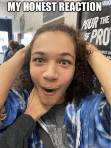 a young man with curly hair is making a funny face in front of a sign that says " pour the pro "