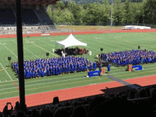 a large group of graduates are gathered on a field with a sign that says ' ucsd ' on it