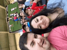 a man and a woman are sitting in front of a large screen that says ' stanley stadium ' on it