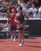 a man in a red shirt is standing next to a woman on a tennis court in front of a perrier sign