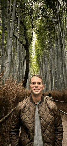 a man in a quilted jacket stands in a forest