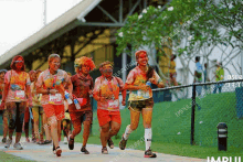 a group of people covered in colored powder are running down a path with impulse running written on the bottom of the photo