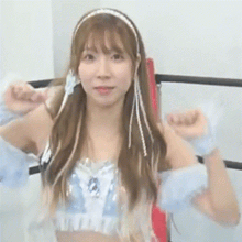 a woman wearing a headband and a crop top is standing in a boxing ring .