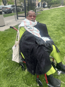 a person in a wheelchair with a bag that says ' a ' on it sits in the grass