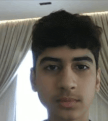 a close up of a young man 's face with a window in the background .