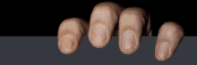 a close up of a person 's fingers peeking out from behind a black wall .